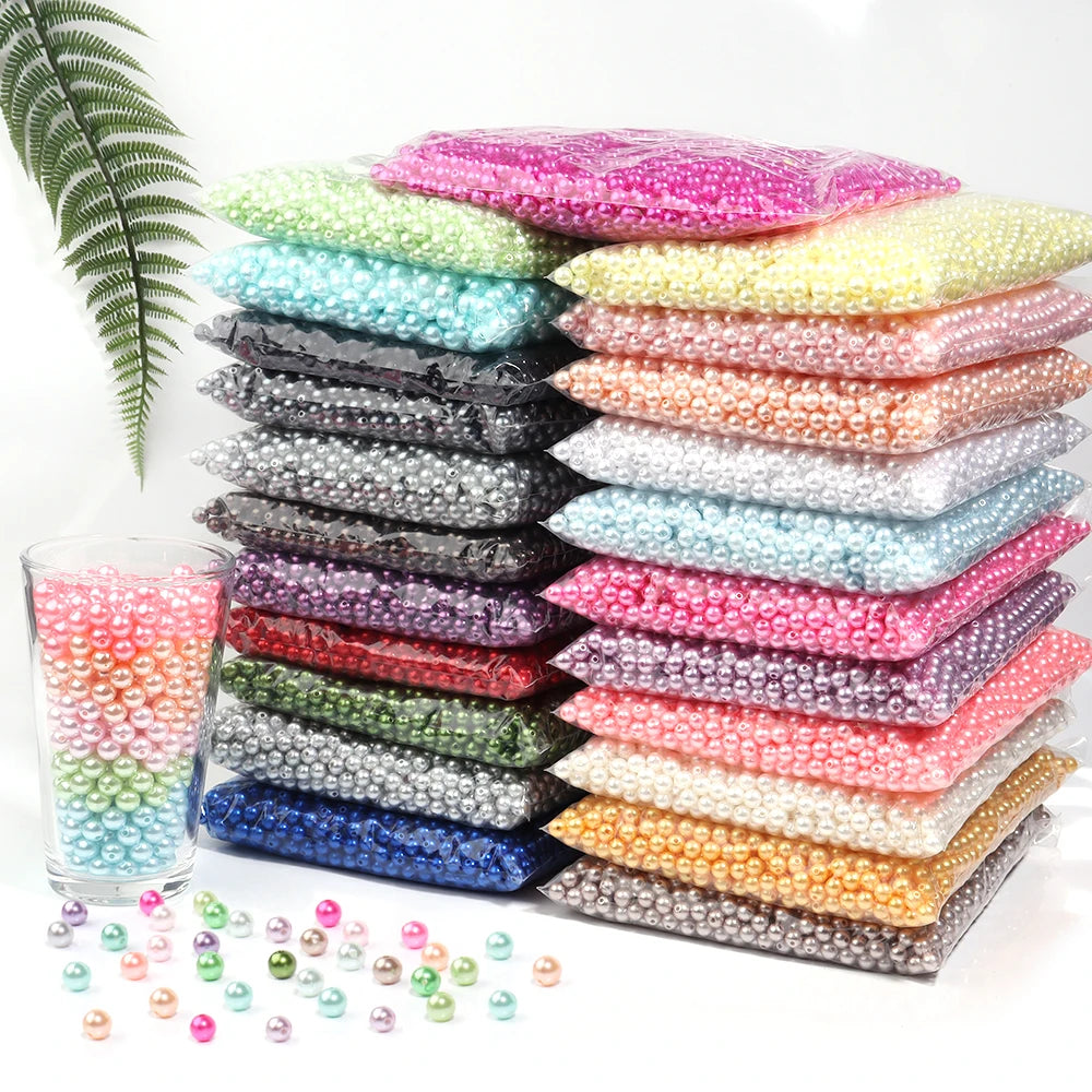 A collection of round imitation pearl beads in various colors and shades stacked on a white surface.