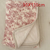 A folded floral muslin baby blanket in beige and pink tones, showing a soft, textured fabric.