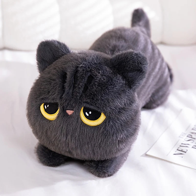 A dark gray plush cat toy with large yellow eyes lying on white fabric.