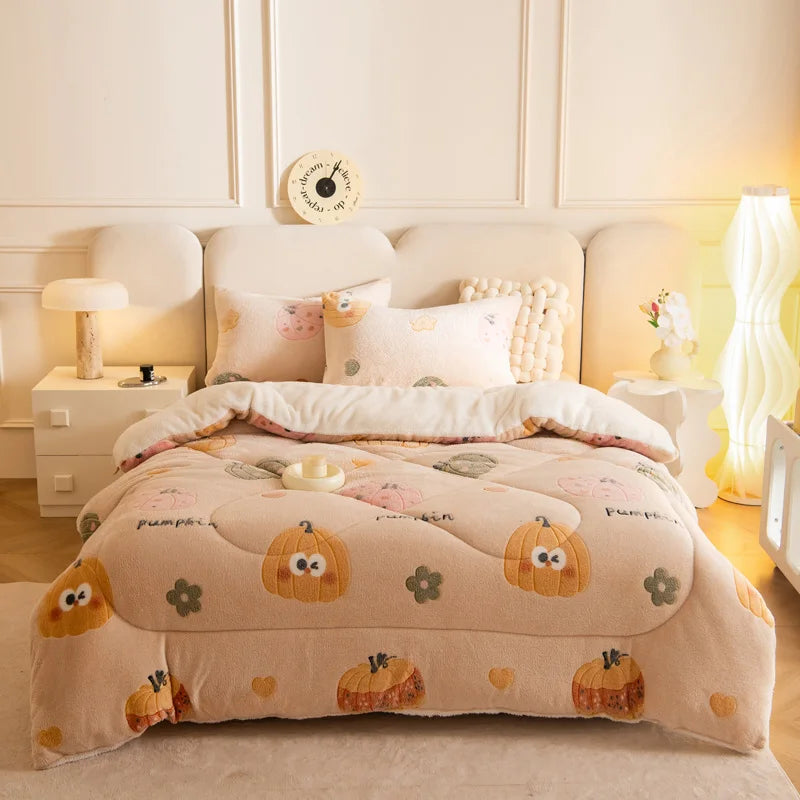 A beige plush throw blanket decorated with small pumpkin patterns is displayed on a bed.
