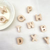 Collection de perles en acrylique de couleur beige clair formant les lettres H O P T W H B D X Y, éparpillées sur une surface
