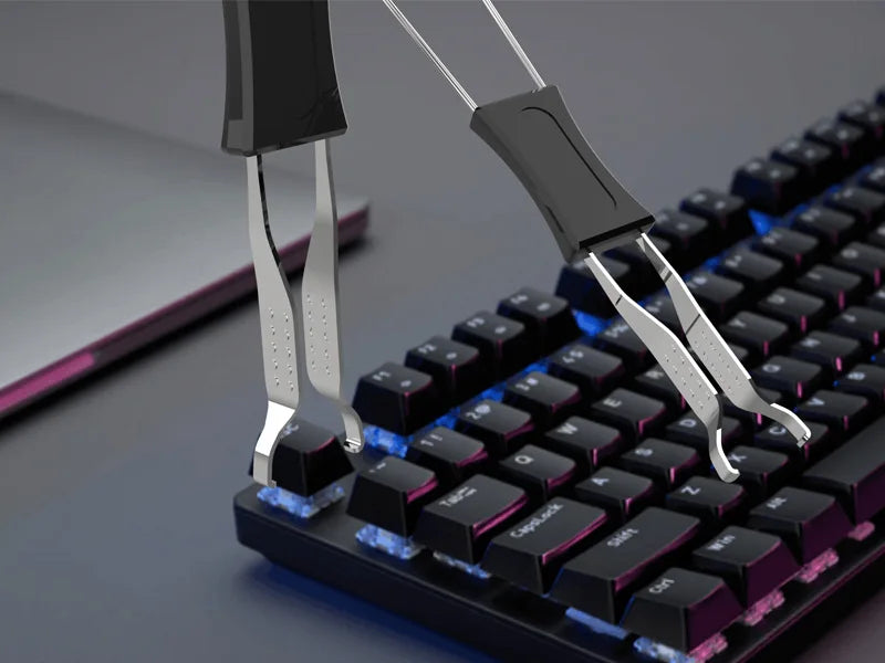 A close-up view of a black mechanical keyboard with a silver keycap puller being used to remove or adjust a keycap.
