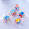 Several clear plastic cubes of various colors, including blue, orange, and yellow, packaged in plastic bags.