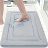 A person's foot is placed on a gray absorbent soft non-slip bath mat for foot soaking or relaxation.