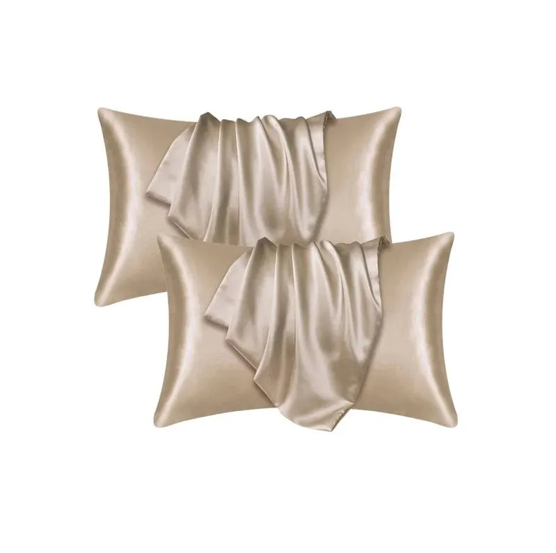 Un juego de dos fundas de almohada de seda satinada de lujo en color beige champán con tela drapeada.
