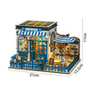 A wooden dollhouse miniature assembly kit featuring a blue and white cafe with an awning and detailed interior.
