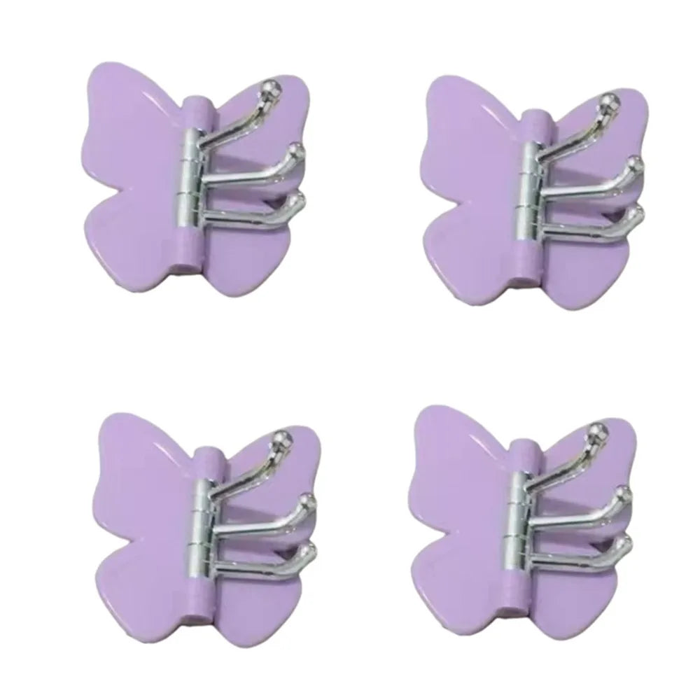 Un juego de ganchos decorativos de mariposa giratoria morados para la pared.