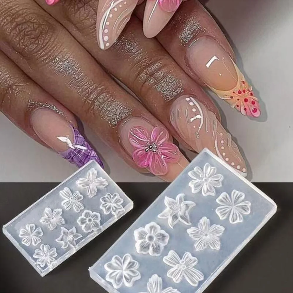 A hand displays intricate white and pink floral nail art designs molded in silicone on fingernails.