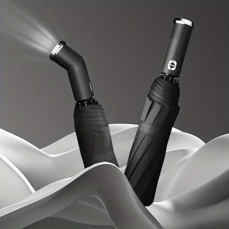 A black automatic three-fold umbrella with an LED light is shown against a gray background.