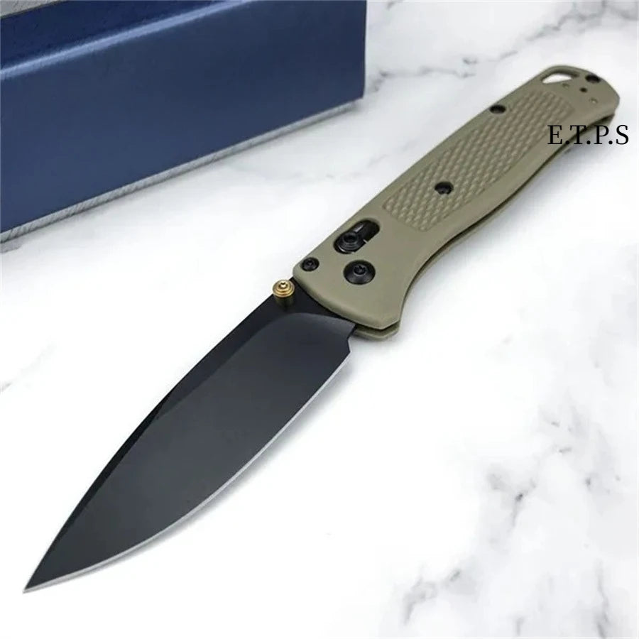 A folding pocket knife with a drop point blade in a light olive green color resting on a white marble surface.