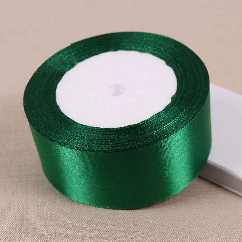 A roll of lustrous satin ribbon in emerald green used for gift wrapping and crafts.