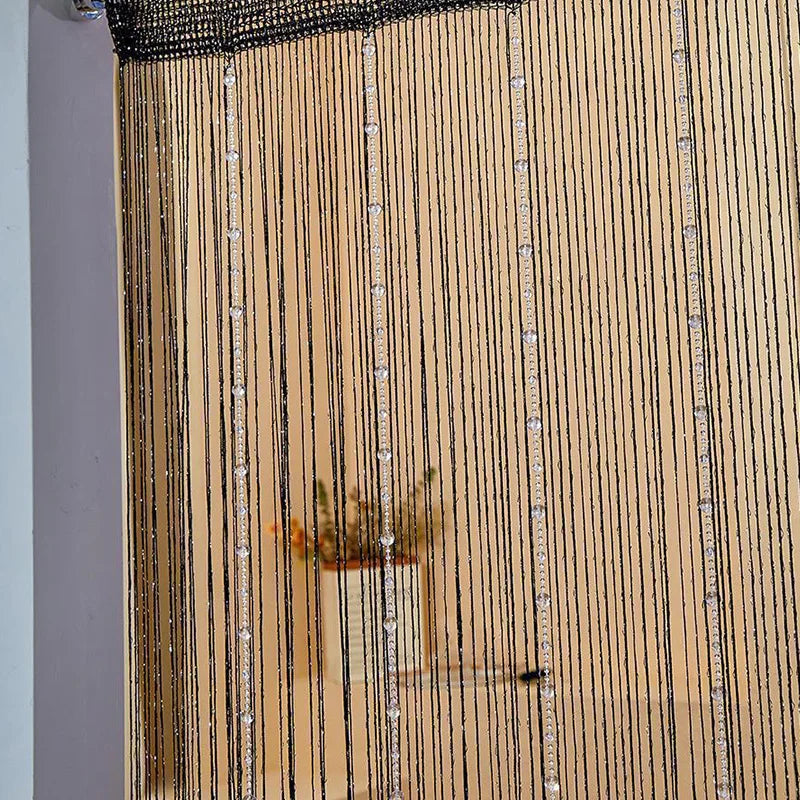 A close-up of a crystal beaded string curtain in a gold tone hanging vertically.