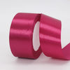 A roll of deep magenta satin ribbon used for gift wrapping or DIY crafts.