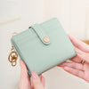 A light mint green bi-fold credit card wallet with a gold chain attached, being held by a person.