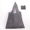 A black and white striped foldable reusable shopping tote with an attached carry pouch.