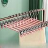 A set of five anti-slip stainless steel hangers with clips for pants and skirts displayed on a wooden rod.