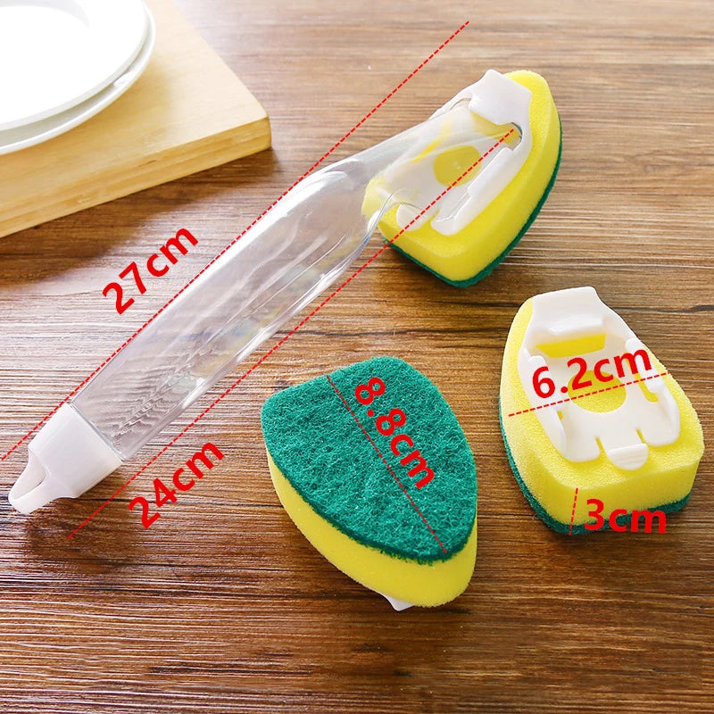 A clear plastic dish wand with a yellow sponge head and a green cleaning pad is shown on a wooden surface.