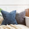 A close-up of a dark blue handwoven chenille texture cushion cover resting on a light beige sofa.