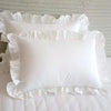 A set of two white minimalist ruffle pillow covers displayed on a white surface.