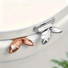 Silver and rose gold touch-free toilet seat lifter with flush button visible on a white toilet bowl.