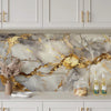 A kitchen backsplash featuring a marble pattern with gold veining installed on light gray cabinetry.