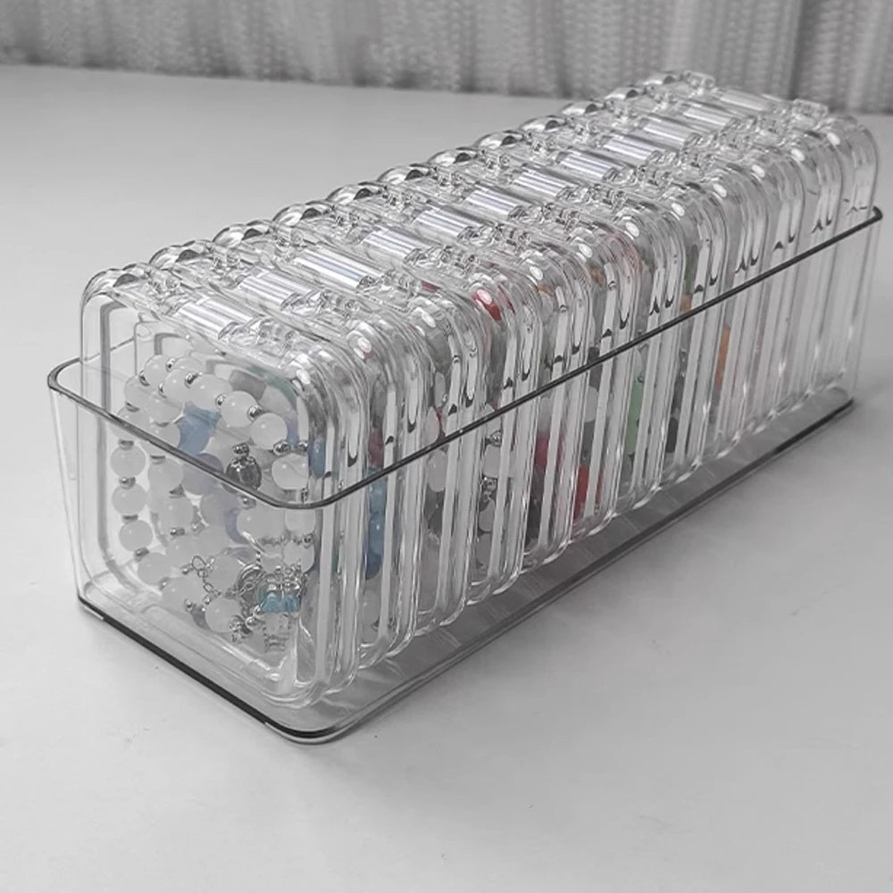 A clear jewelry organizer box with multiple secure compartments for storing rings and other small items.