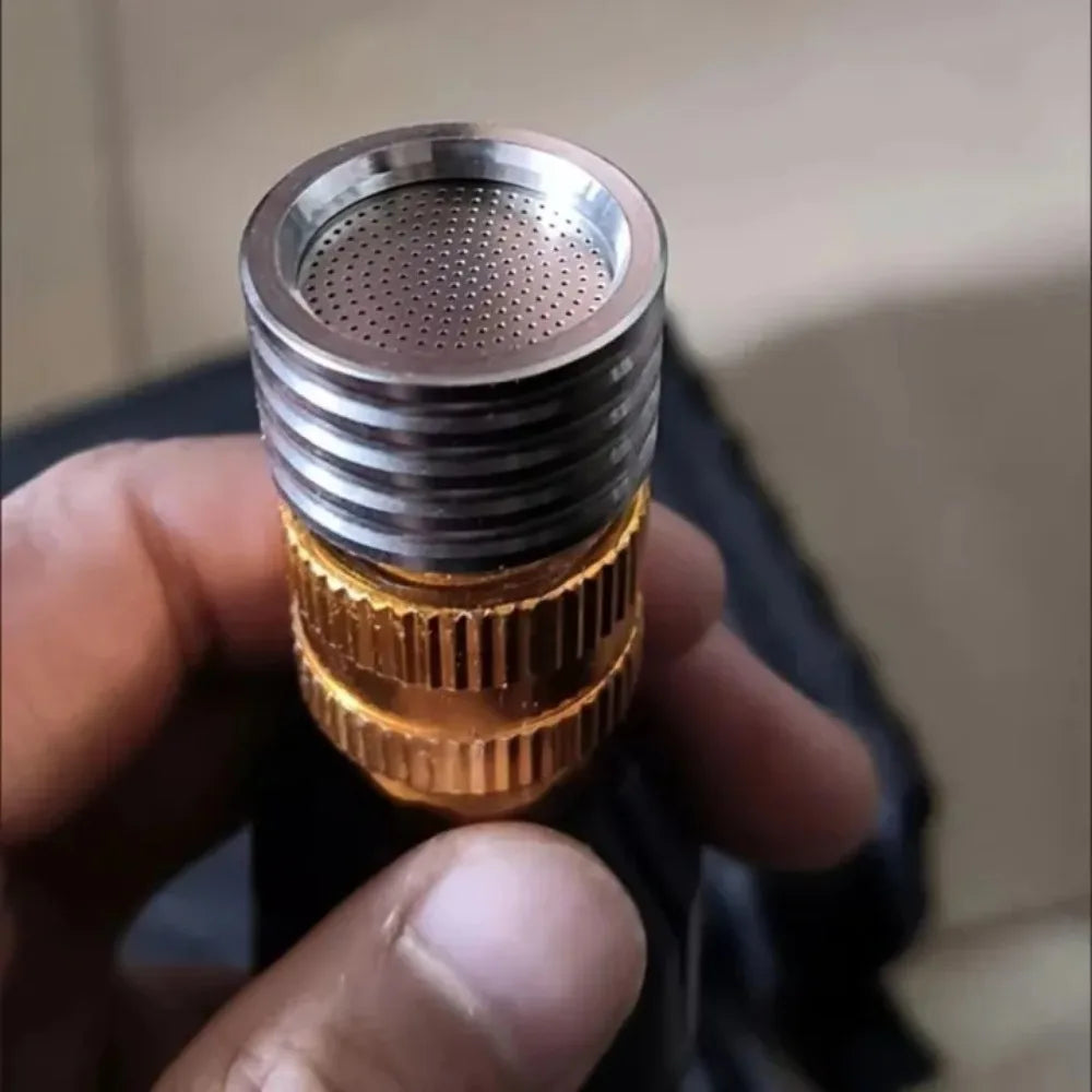 A close-up of a stainless steel high-pressure washer nozzle with a brass quick connect fitting being held in a hand.