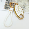 A gold-colored key fob with a white cord attached, featuring five buttons for a Nissan vehicle.