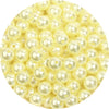 A close-up view of small, round, pale yellow imitation pearl beads for jewelry making.