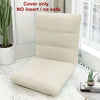 A beige foldable floor sofa cover for a single seat displayed on a white rug next to a window.