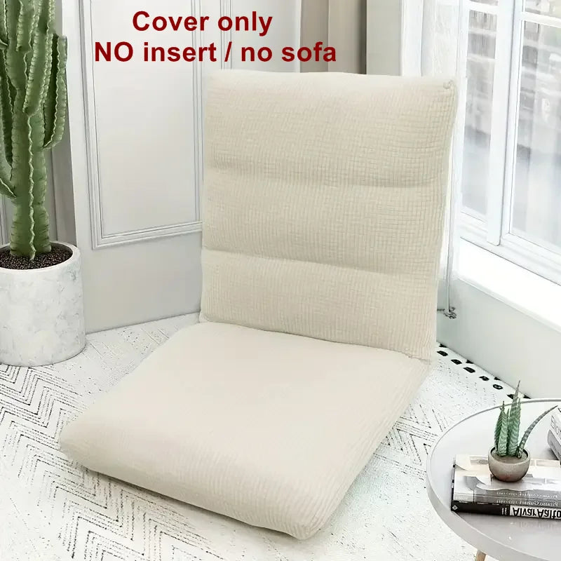 A beige foldable floor sofa cover for a single seat displayed on a white rug next to a window.