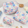 A pink and blue patchwork quilted makeup bag resting on a white surface next to a wooden object and makeup brushes.