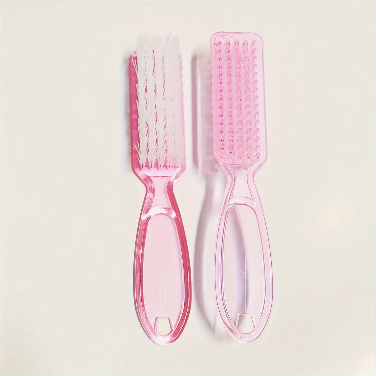 A set of pink nail art brushes with long handles, including a flat brush and a fine-tipped brush.