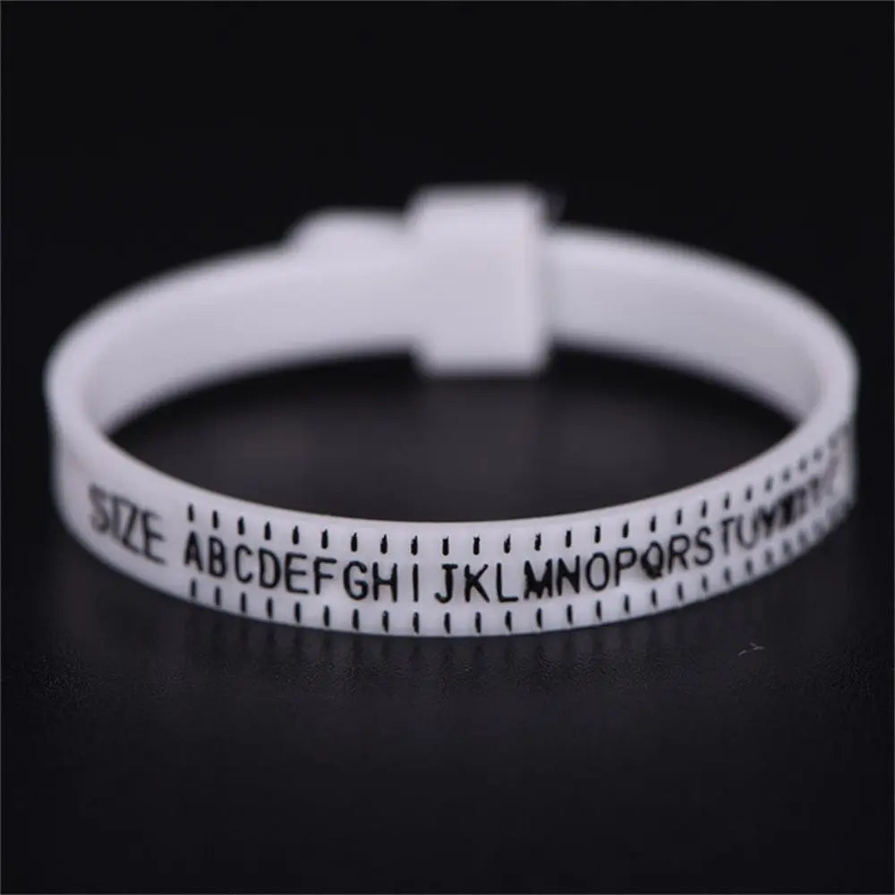 A white ring sizer measuring tool with a letter scale is shown against a dark background.