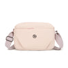 A light pink nylon crossbody bag with a flap and strap is shown against a white background.