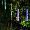 Vertical LED path lights with color-changing bubbles illuminate lush green foliage in a dark garden.
