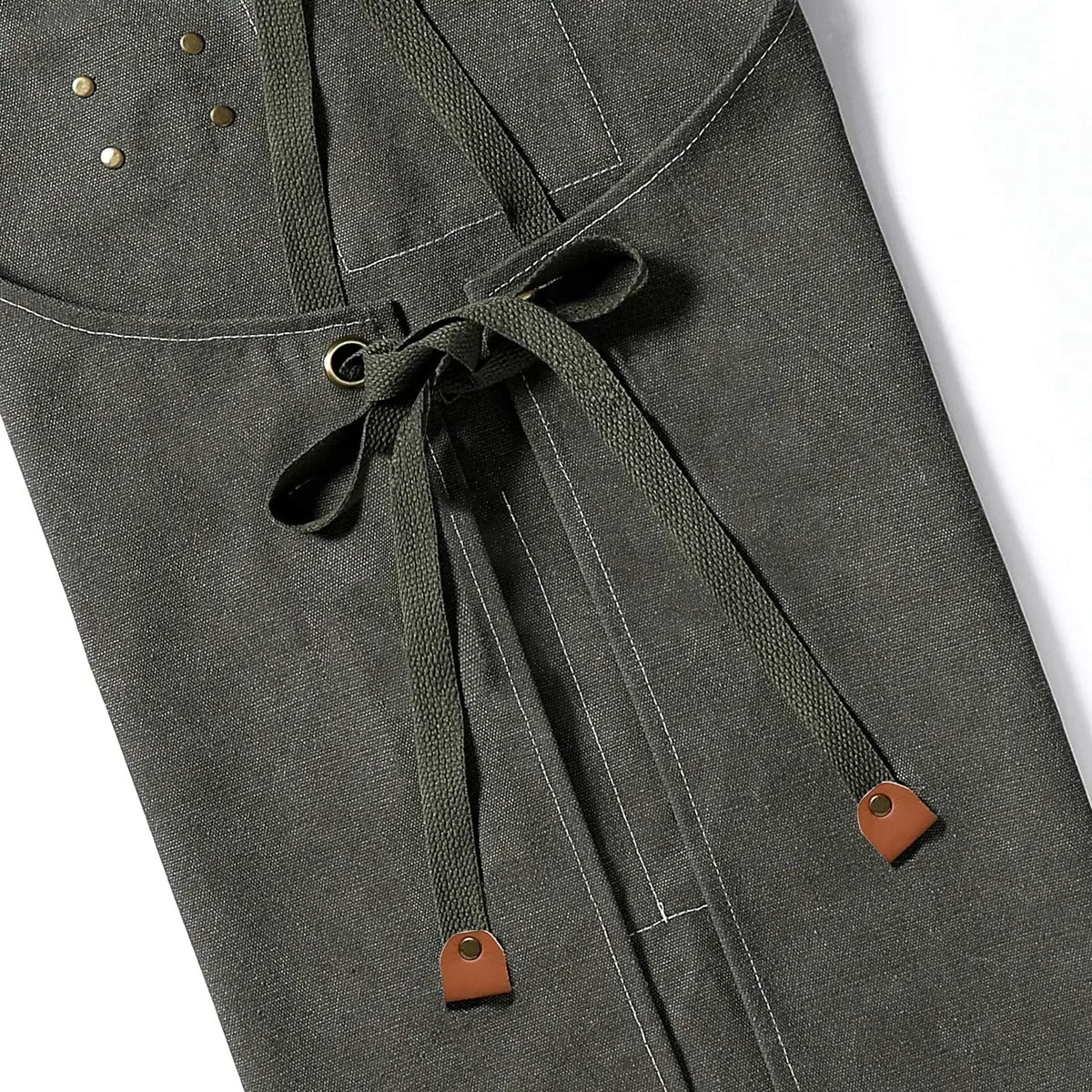 A close-up of a dark olive green cotton canvas apron with drawstring ties and cross-back straps.
