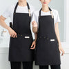A woman wearing a black waterproof canvas chef apron over a white t-shirt.