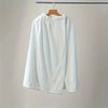 White quick-dry wearable bathrobe towel hanging on a wooden hanger against a light gray wall.