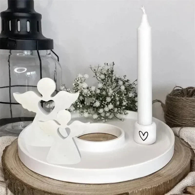 White angel-shaped silicone mold for resin and crafting placed on a wooden surface with a candle.