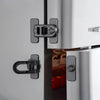 Close-up of a modern stainless steel non-drill child safety door lock installed on a kitchen appliance cabinet.