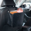 A black fabric organizer is placed on a car seat, holding a pink glass and a small orange item.