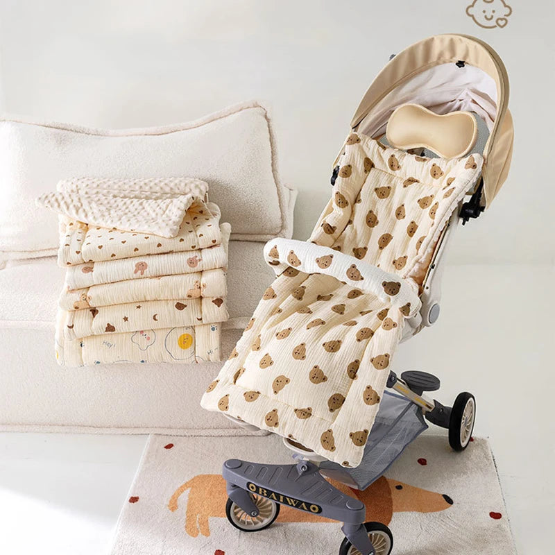 A beige baby stroller seat cushion with padded support is shown on a light-colored fabric and a small wooden floor.