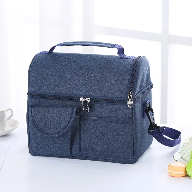 A dark blue insulated lunch bag with a handle and zippered compartments is shown on a white surface.