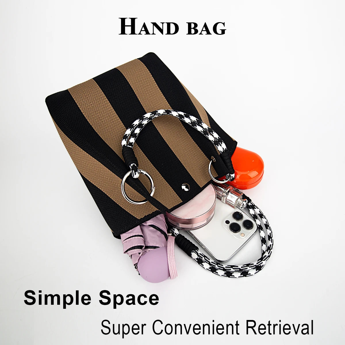 A hand bag featuring a striped fabric and a black leather strap with a silver ring detail.
