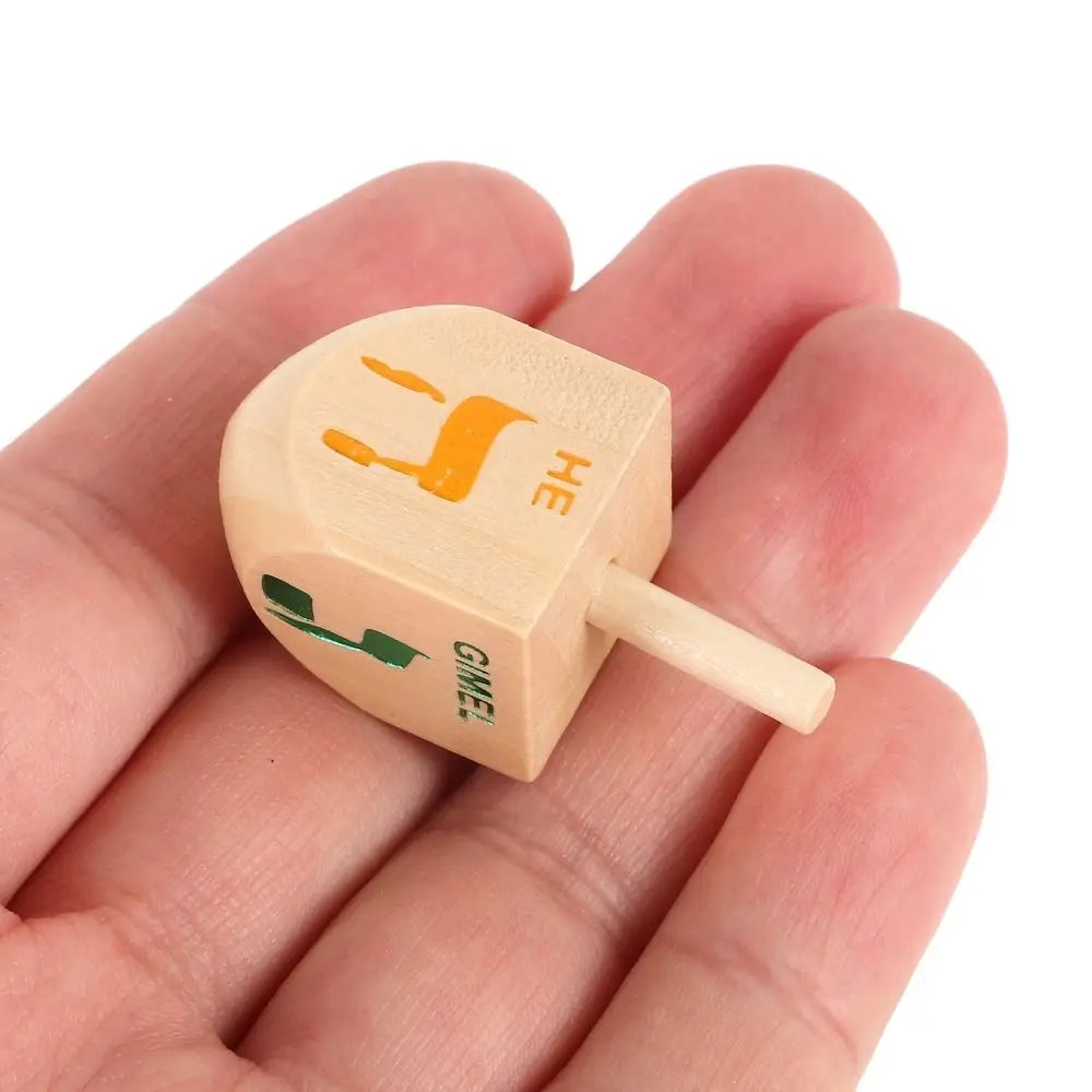 A wooden spinning top with the letter H engraved on it, held in a person's hand.