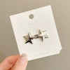 Silver star-shaped metal brooch and belt buckle set on a white card
