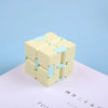 A light yellow infinity magic cube fidget toy with light blue accents resting on a white surface.