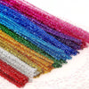 A vibrant rainbow of colorful chenille craft stems arranged diagonally on a white background.