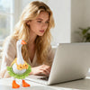 A woman is working on a laptop with a mini desk goose outfit set in front of her.